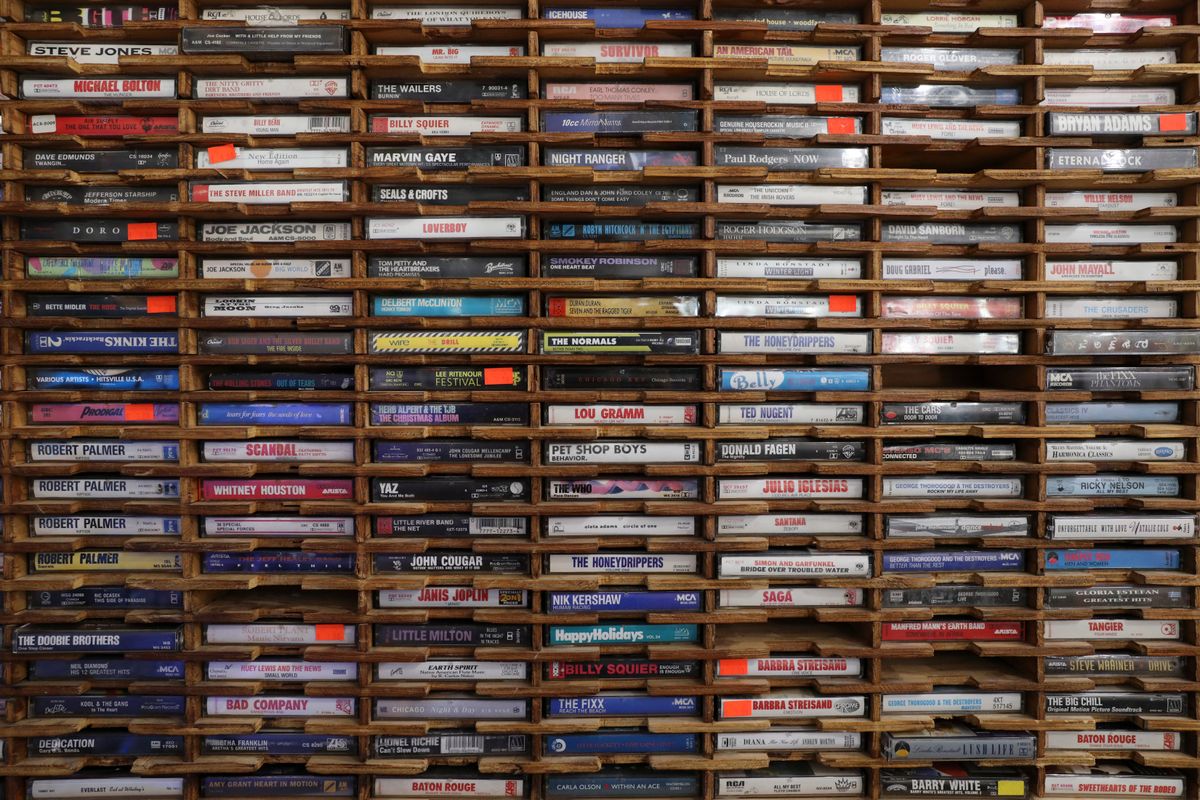 Collection de cassettes audio vintage rangées sur des étagères en bois