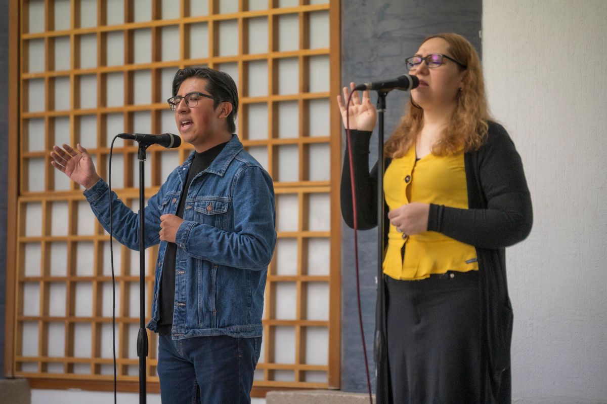 Duo homme-femme interprétant une chanson au micro sur une scène en intérieur