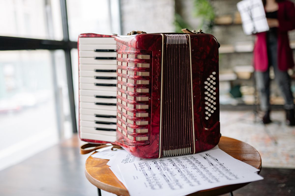 Accordéon rouge posé sur un tabouret à côté de partitions de musique